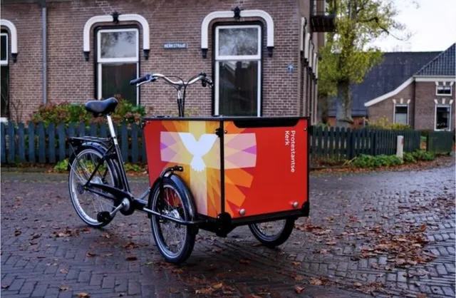 Bakfiets van Protestantse Kerk Nederland met een kruis en een duif erop.
