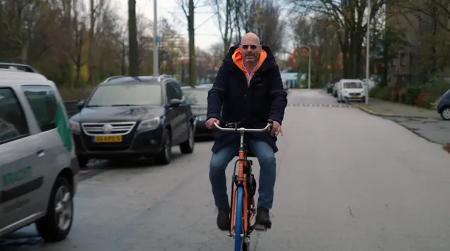 Neo de Bono fietst door een rustige, brede staat. Neo was tot een paar jaar geleden een succesvolle internetondernemer. Inmiddels is hij community builder in de wijk Moerwijk (Den Haag).